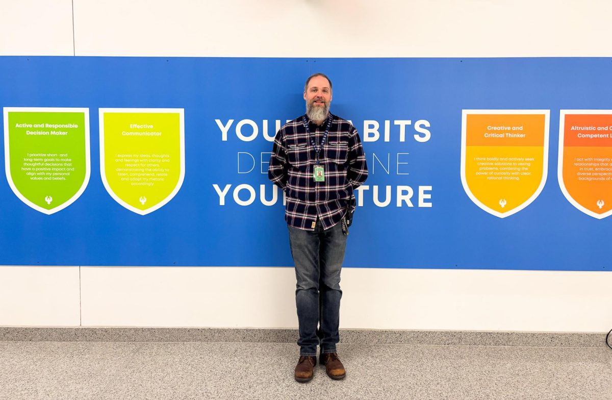 Mr. Hewlett in front of the STEAM Habits sign